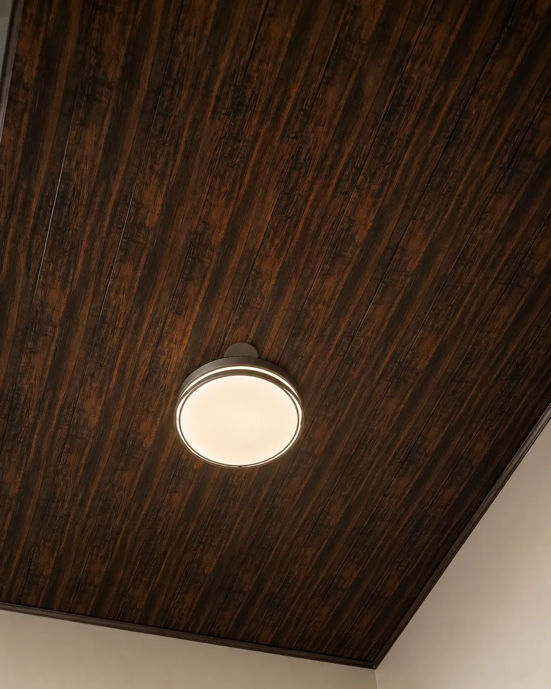 Cielo revestido con acabado tipo madera oscura y luminaria central